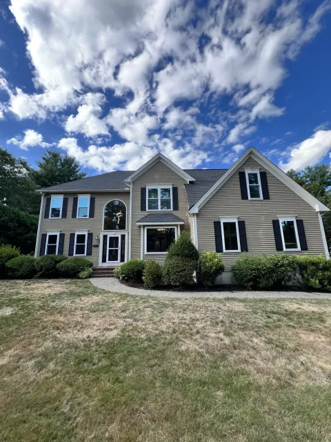 Colonial home with replacement windows under a cloudy sky