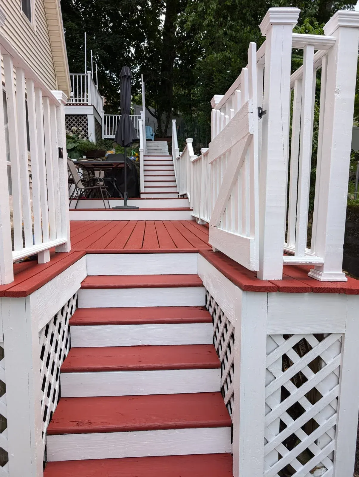 Freshly painted red and white deck with stairs, railings, and outdoor seating