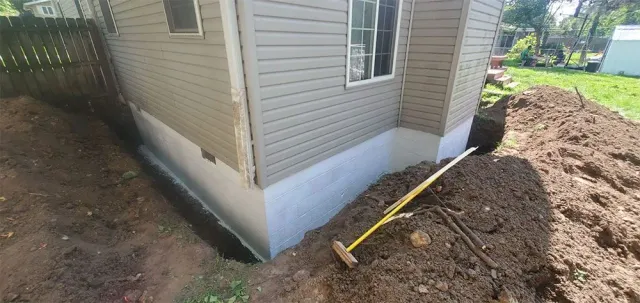 A house under construction with an excavated trench along the foundation.