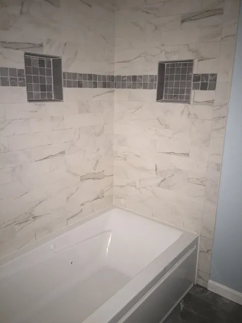 Shower installation with marble tile and accents from  Summerlin Floors