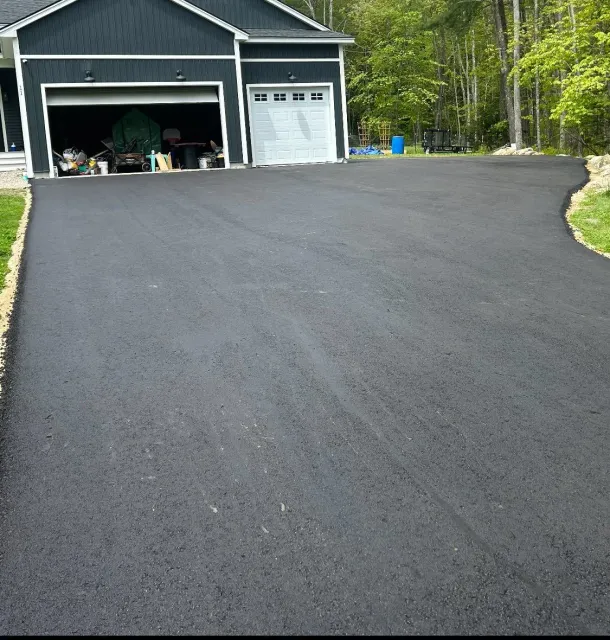 A driveway leading to a black house with a white garage door