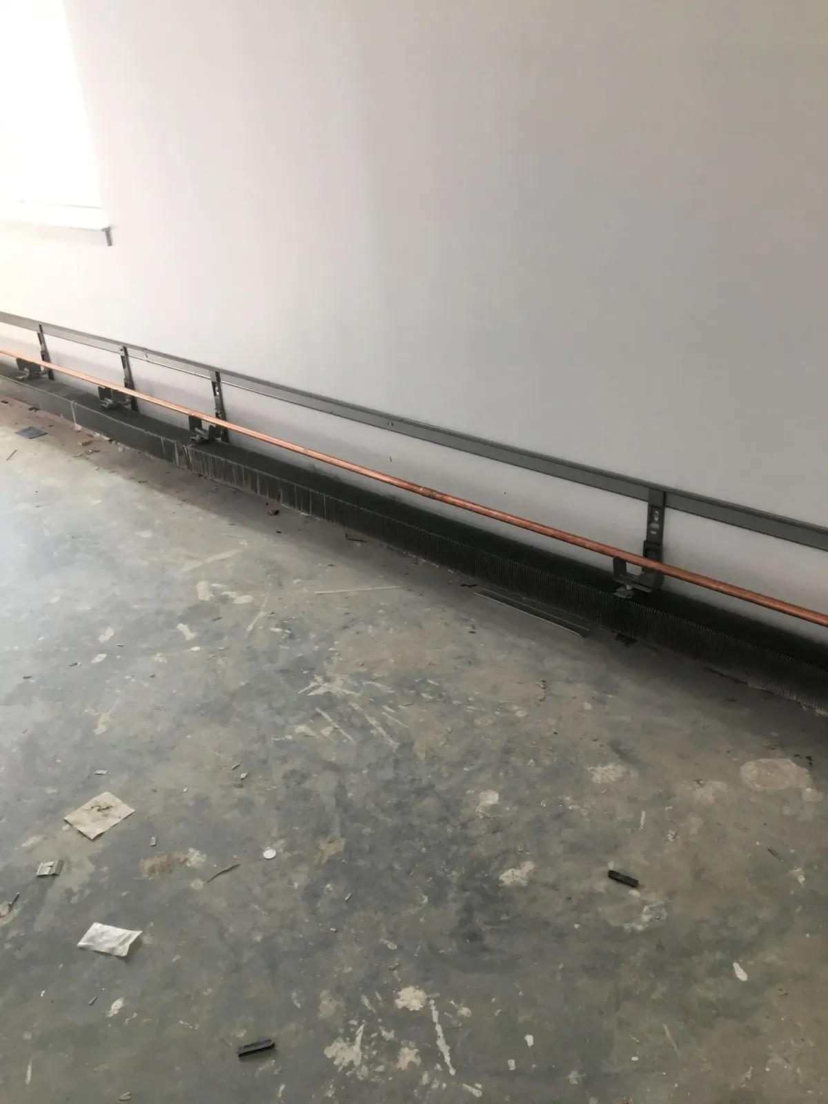 A room with a concrete floor and a metal railing on the wall.