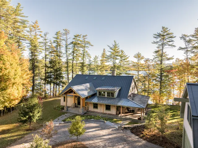 Lakeside home with a grey roof surrounded by autumn trees in Maine.