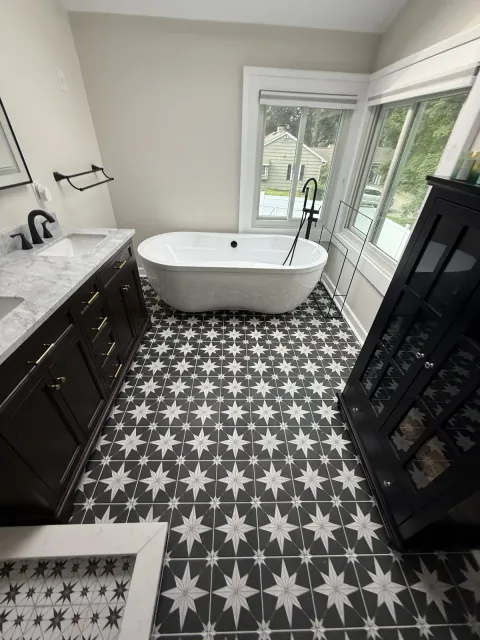 Bathroom with a freestanding tub, patterned tile floor, dark vanity and a skylight