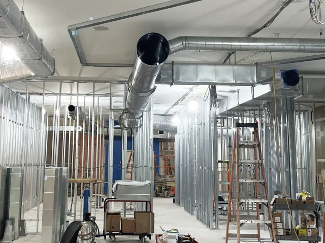 Commercial building with exposed metal studs and HVAC ductwork during construction.
