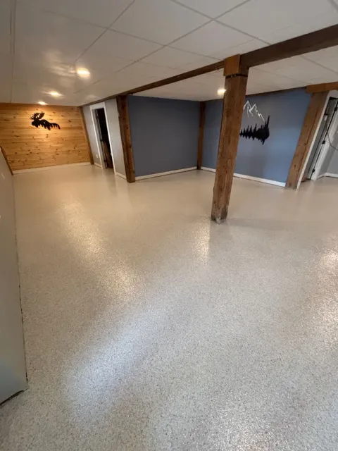 Basement with speckled flooring, wooden beams and wall accents, and recessed lighting.