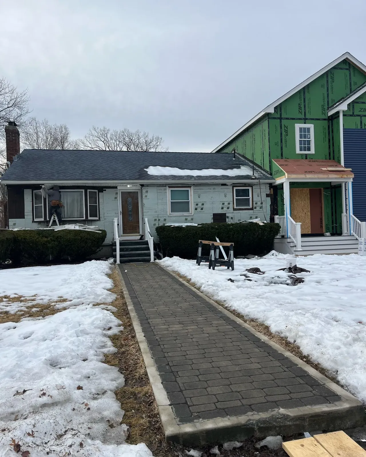 A house with snow on the ground and a walkway leading to it.