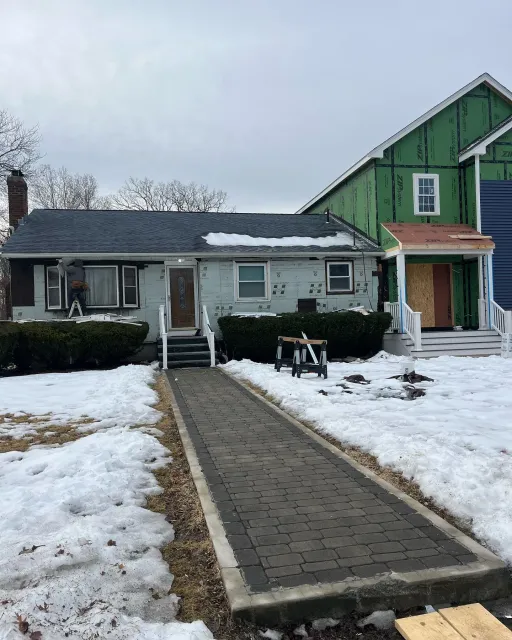 A house with snow on the ground and a walkway leading to it.