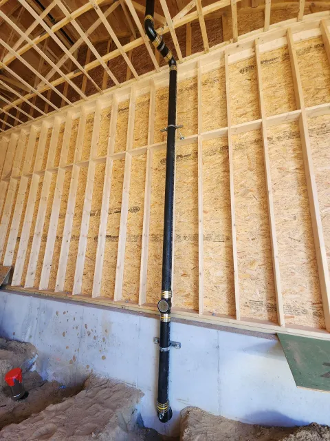 A pipe is hanging from the ceiling of a building under construction.