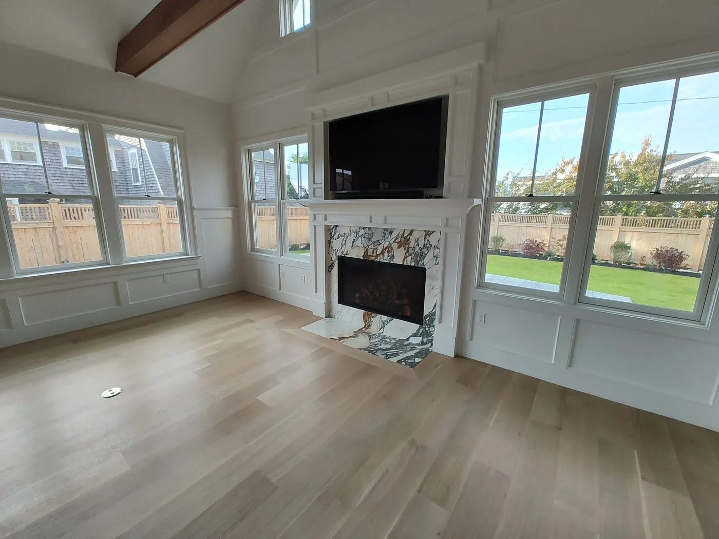 Living room remodel with a fireplace, hardwood floors and large windows