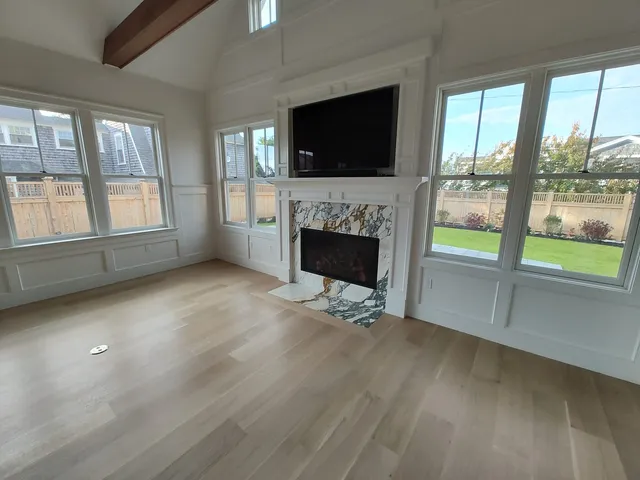 Living room remodel with a fireplace, hardwood floors and large windows
