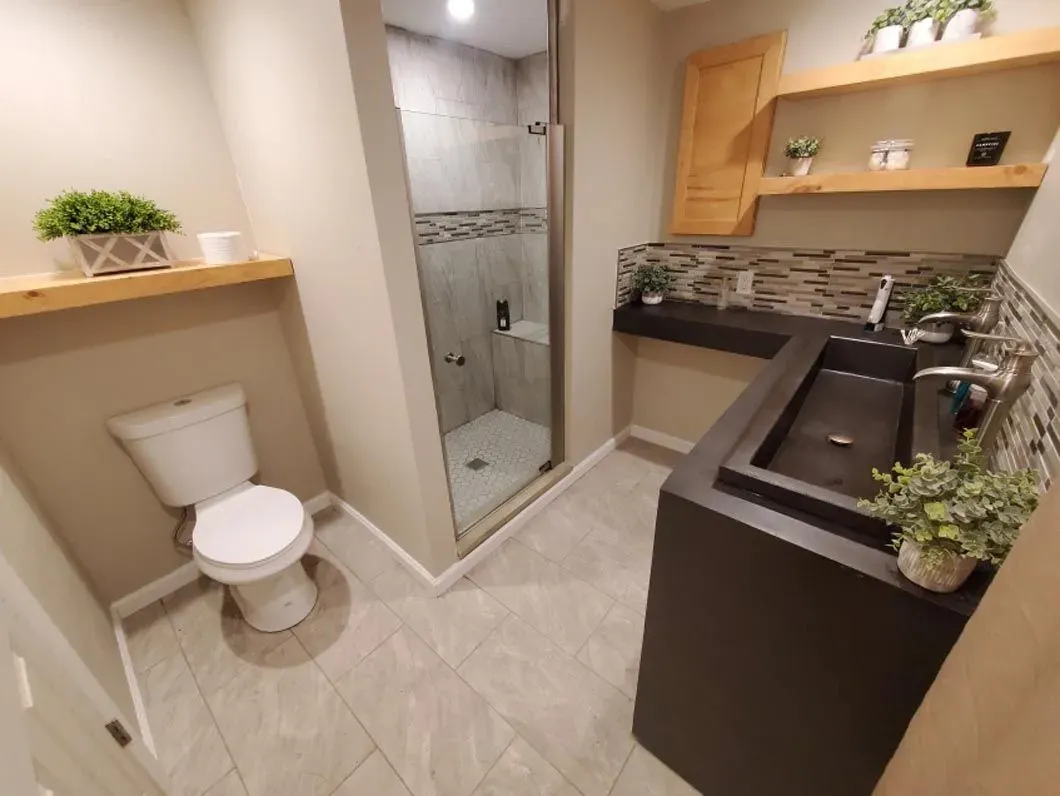 A bathroom with a toilet , sink and shower.