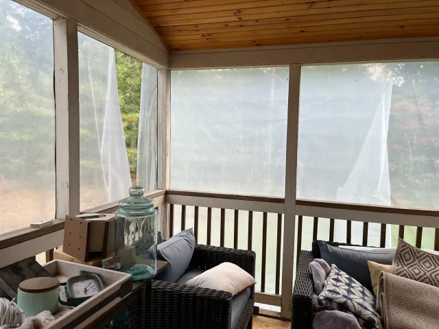 A covered in porch with a couch and chairs