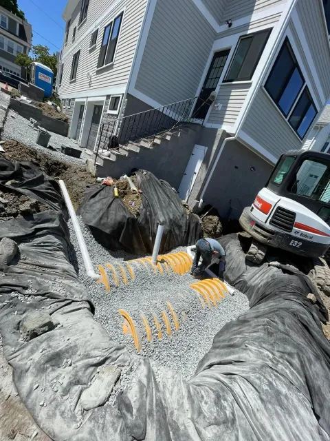 A man is working on a septic system in front of a house.