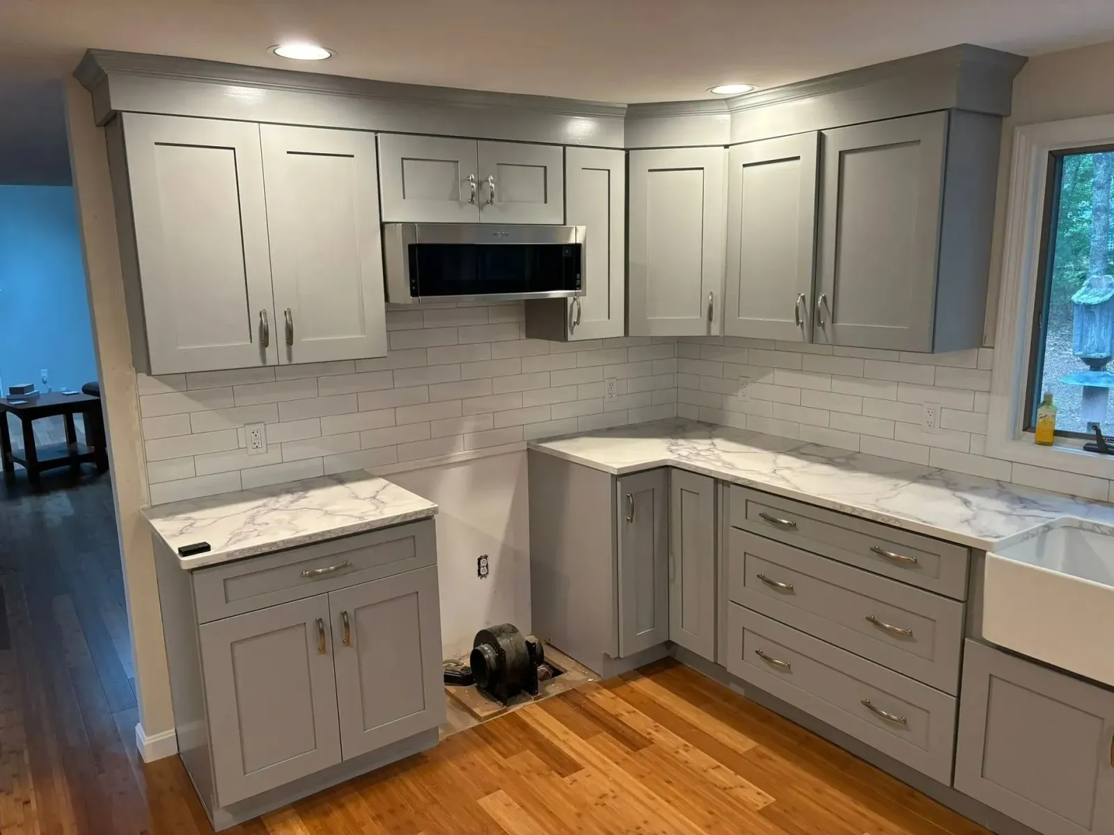 Gray kitchen cabinets with white countertops and white subway tile backsplash.