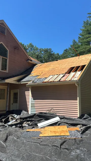 House roof under renovation with exposed wooden beams and scattered debris.