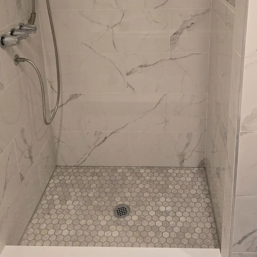 Marble-look porcelain shower with hexagon mosaic floor and built-in bench by Link Services Pro in Westborough, MA