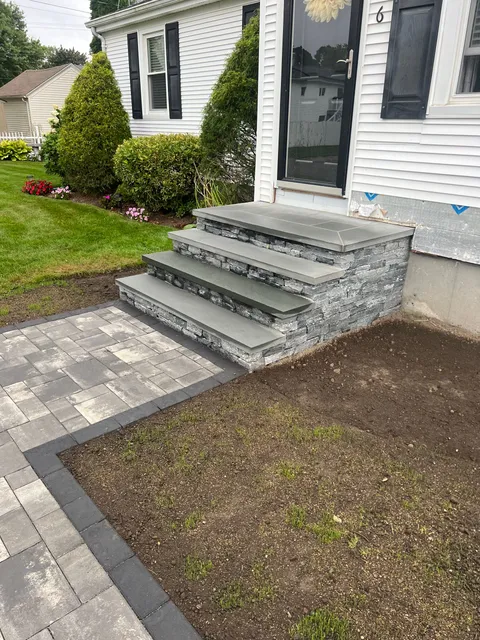 A stone walkway with stairs leading up to the front door of a house.