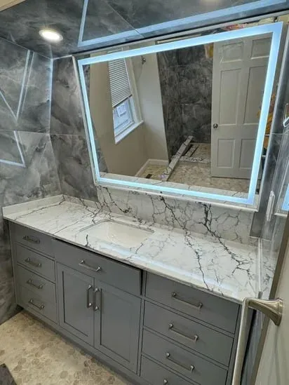 Somerville bathroom remodel showing grey vanity, marble countertop, and LED mirror.