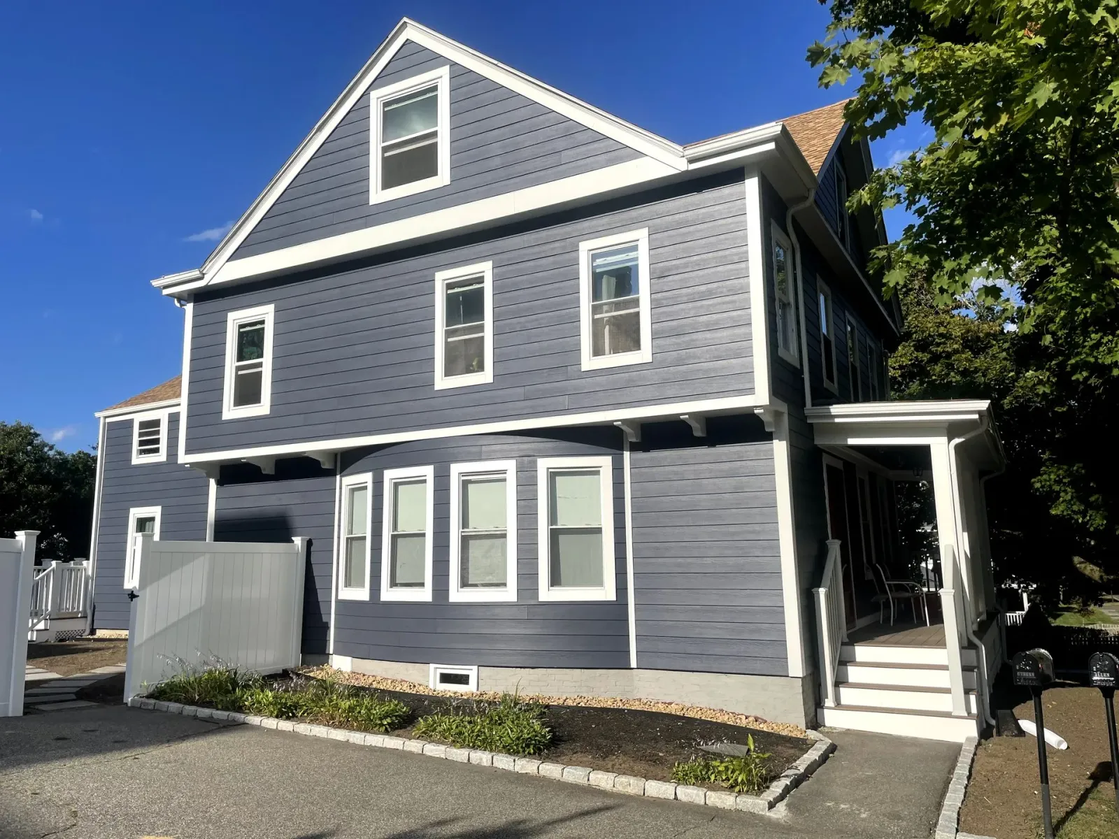 The side of a house with a gray siding and two windows.