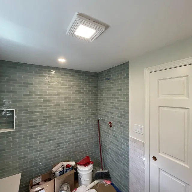 Boston Light & Power electrician installing a bathroom fan and light combination in Milton, MA.