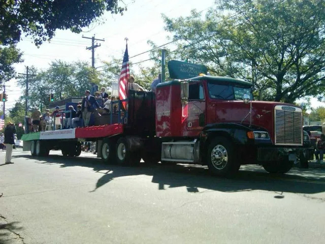 A red semi truck is pulling a float down a street