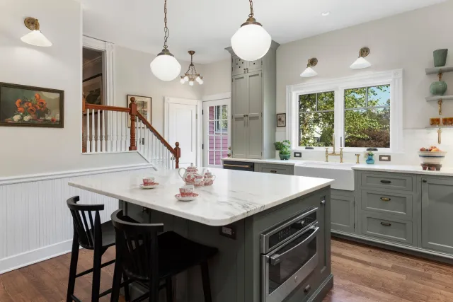 Modern kitchen with large island, gray cabinets, pendant lights, and a window over the sink
