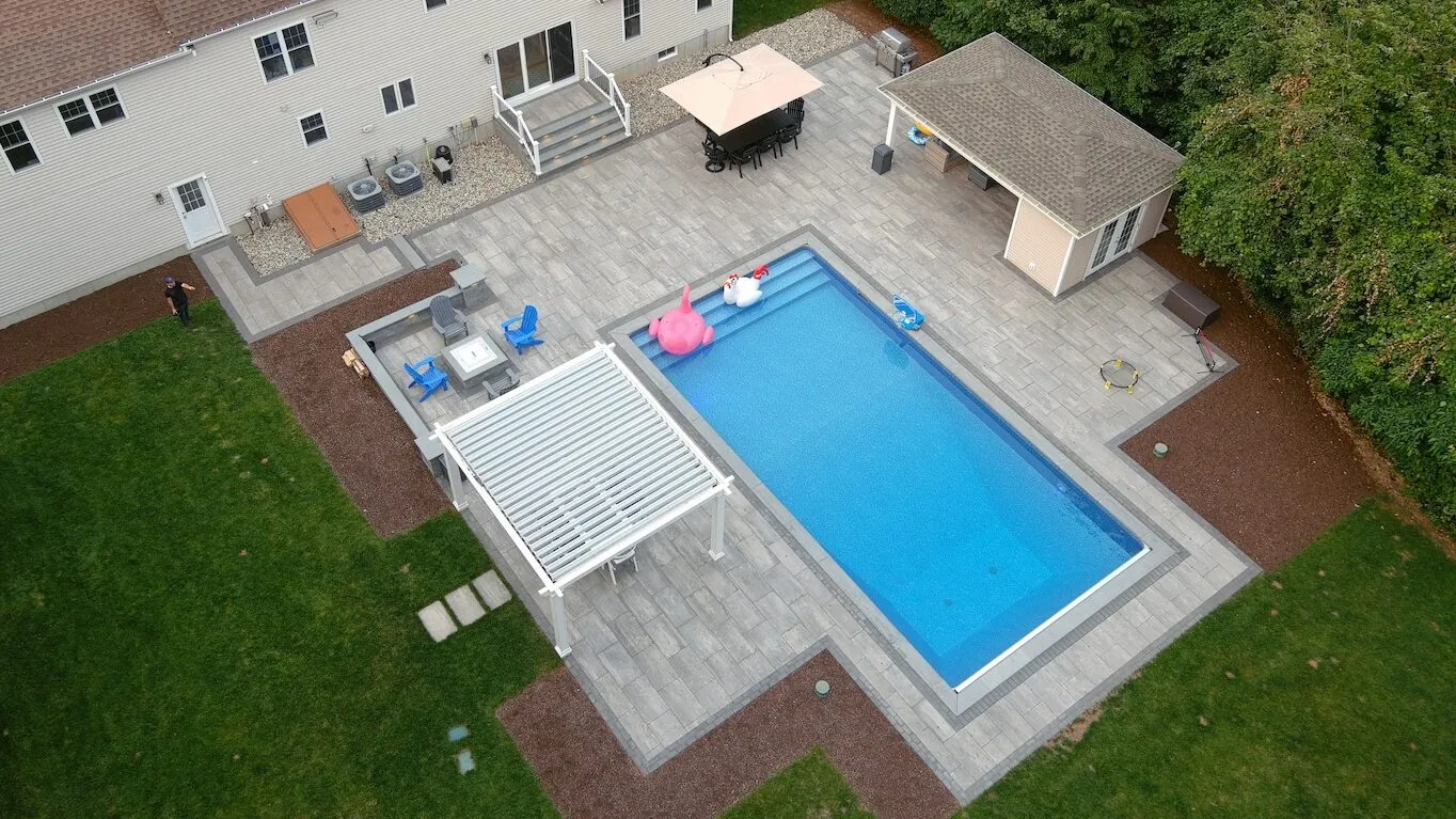High-angle aerial view of cabana, paver patio, built-in fire pit and outdoor kitchen in Lakeville, Massachusetts