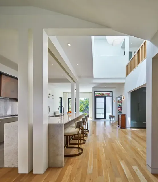 Bright modern open-plan home interior with wood floors, kitchen island stools, and a lofted ceiling