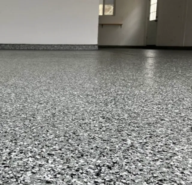 Empty room with a terrazzo floor and a white wall, with a window on the right side.