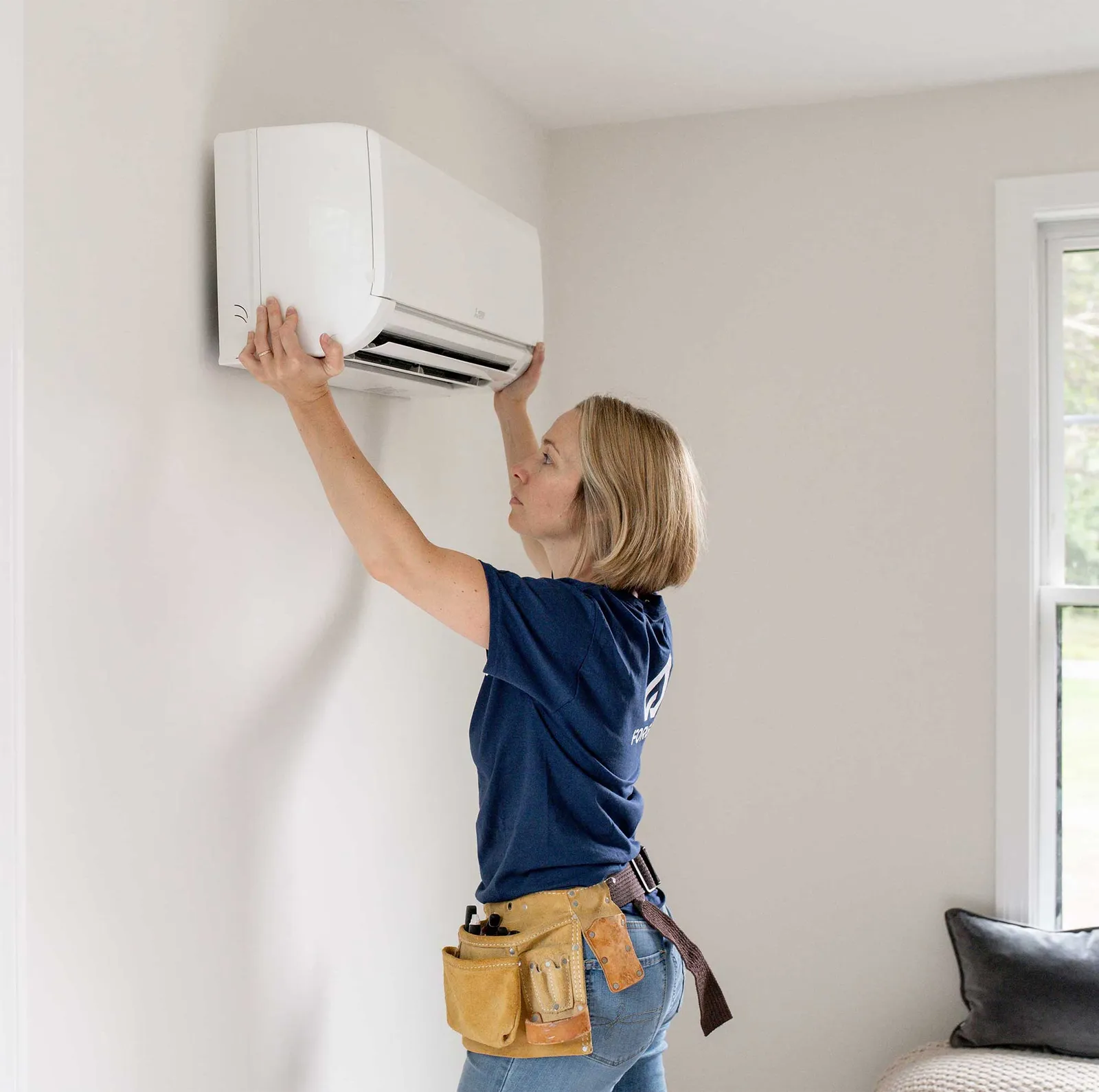 Forge HVAC technician hanging a mini-split head in a massachusetts home
