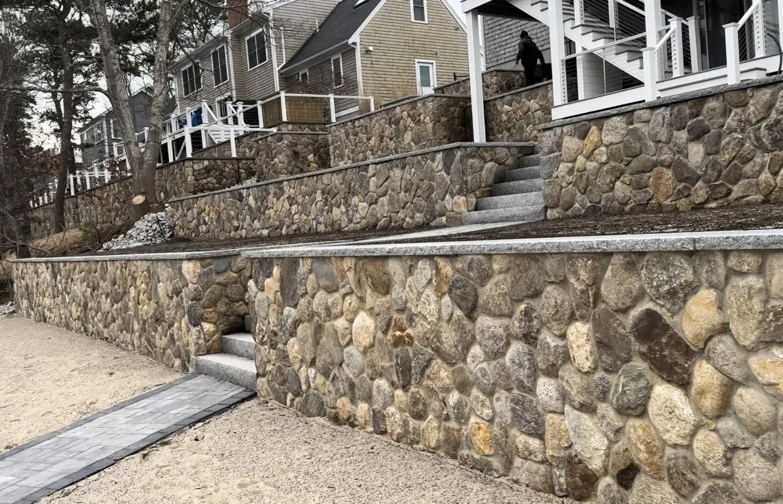 Stone retaining wall and terraced walkway beside a Cape Cod home