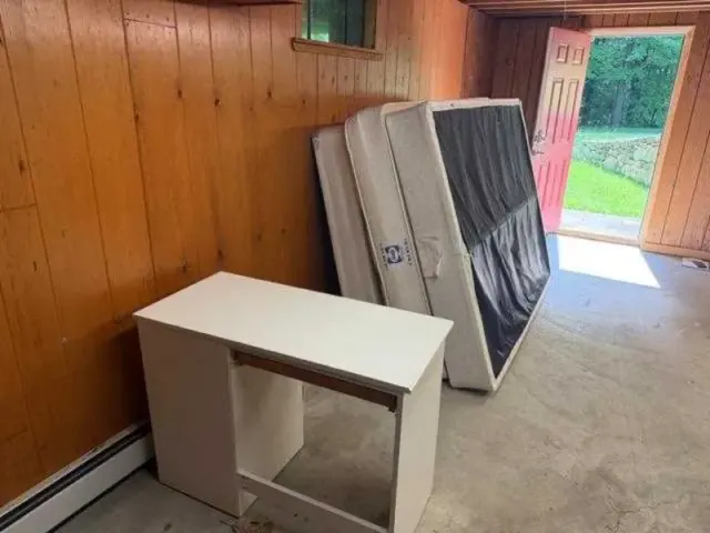 A room mid-cleanout with mattresses and furniture staged for removal