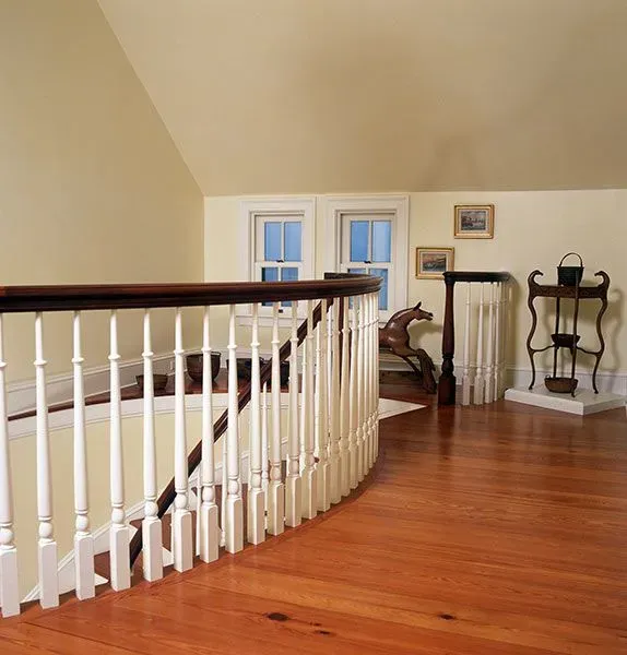 A staircase with a white railing and a wooden floor