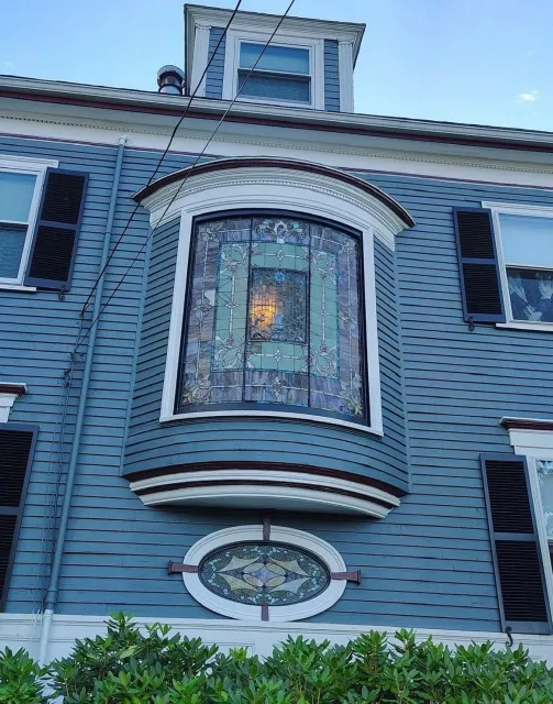 Blue house facade with a bay window, white trim, and black shutters.