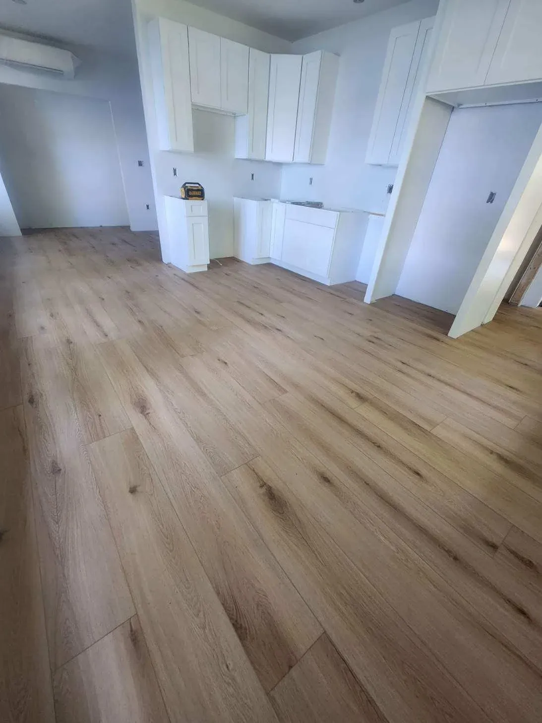 Empty kitchen with white cabinets and wooden flooring in a new or renovated home.