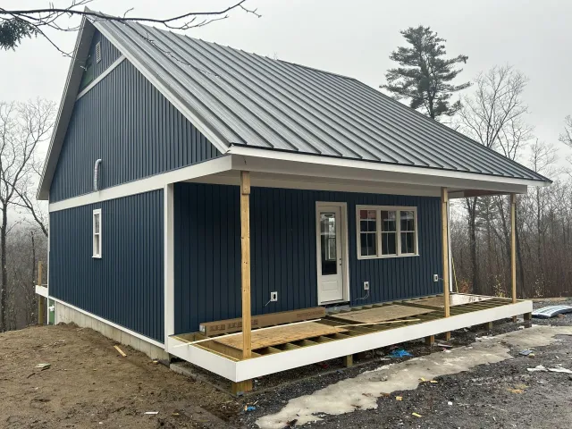 A blue house with a metal roof and a porch.