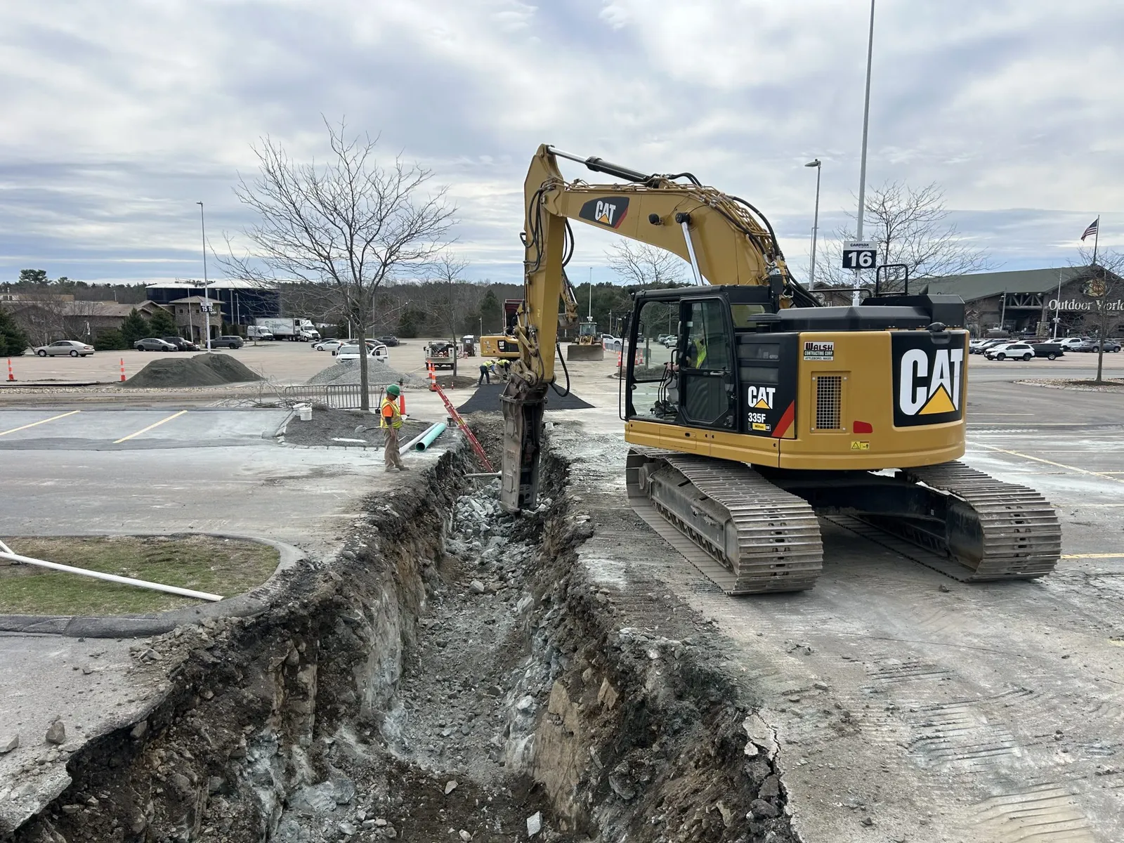 Walsh Contracting Corp performing utility installation in the Bass Pro Shops parking lot, using heavy equipment to install underground infrastructure.
