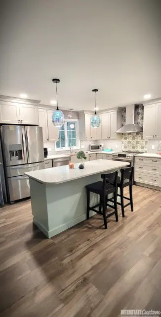 Spacious kitchen remodel with large island, quartz countertops, shaker cabinets, stainless steel appliances, and elegant pendant lighting.