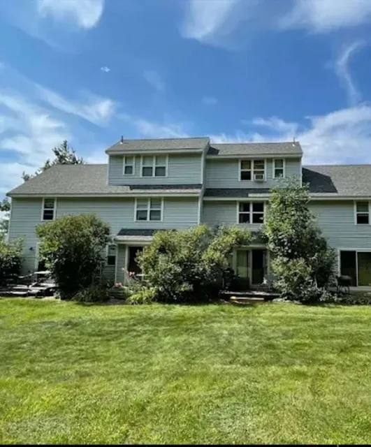 Two-story house with trees and lawn, sunny day