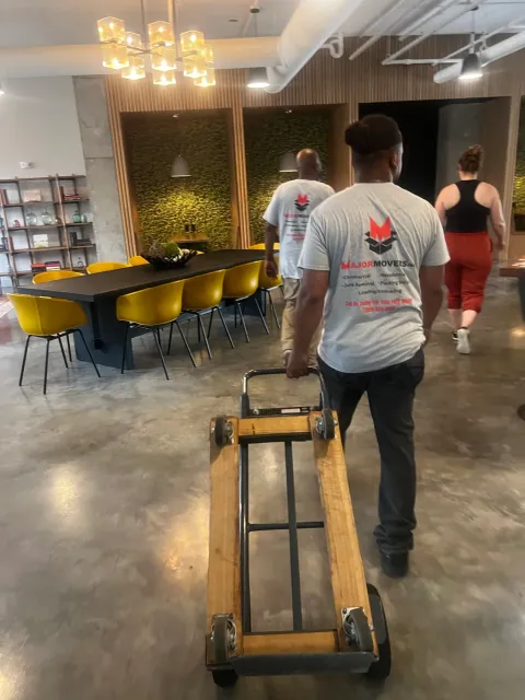 Major Movers crew moving furniture through an office with a four-wheel dolly