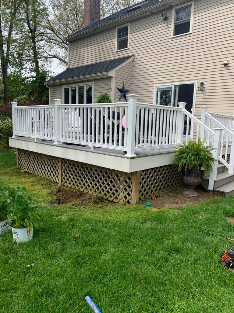 A deck with stairs and steps in the middle of a yard.