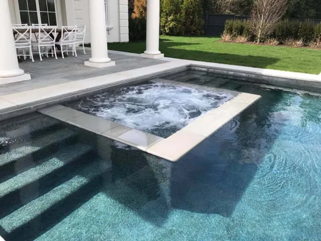 A large swimming pool with a hot tub in the middle of it.