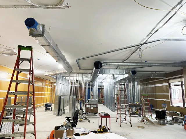 Interior construction site with ladders, metal studs, and ductwork