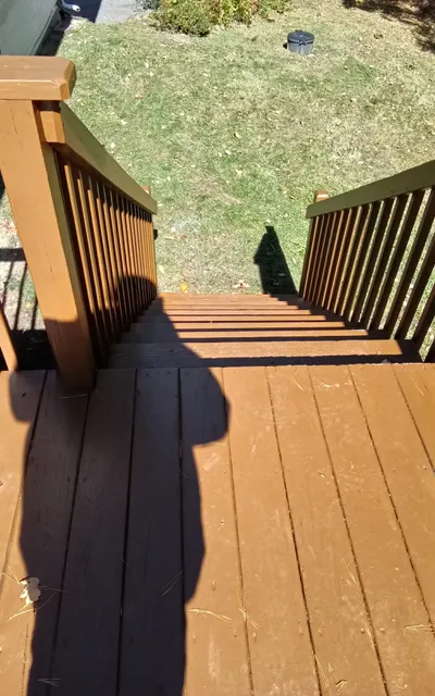 Brown-painted deck boards, stairs and railing after the repair and finish work.