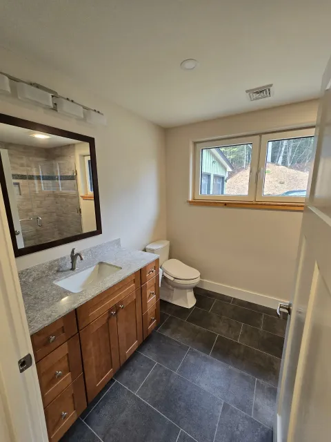 A bathroom with a toilet , sink and mirror