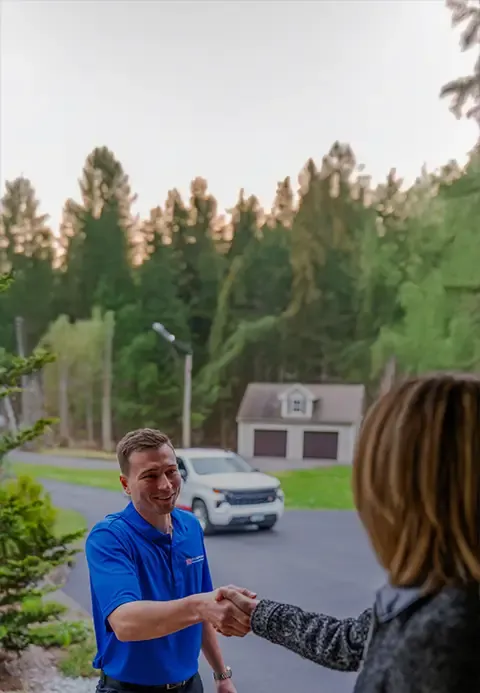 A Door Systems employee shakes hands outdoors with a woman.