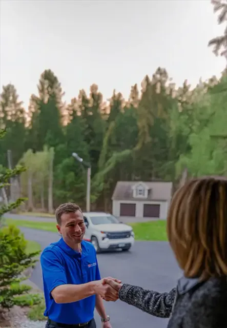 A Door Systems employee shakes hands outdoors with a woman.