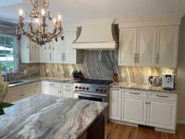 Kitchen with white cabinets, marble countertops, stainless steel appliances, and a chandelier.