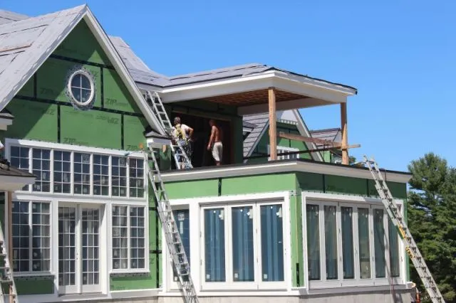 a green house with roofing contractors working on a flat metal roof in CT